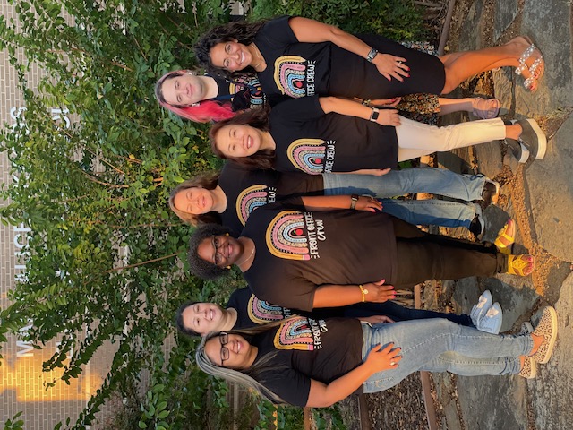 The Skaggs Office Staff smiling in front of a bush in their black Skaggs Office Team shirts.