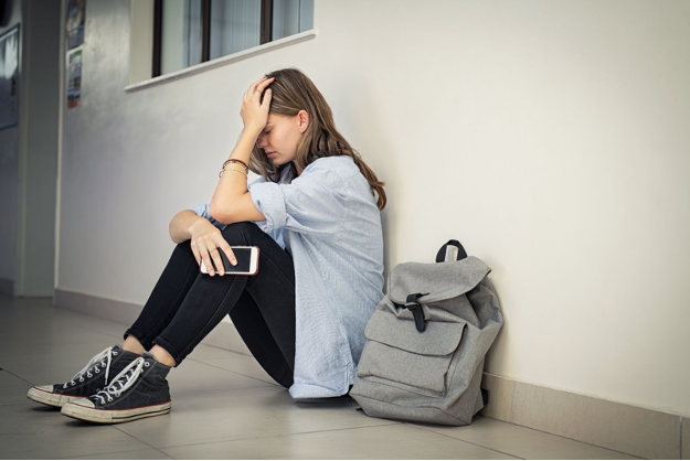 Student sitting on the floor with hand on forehead