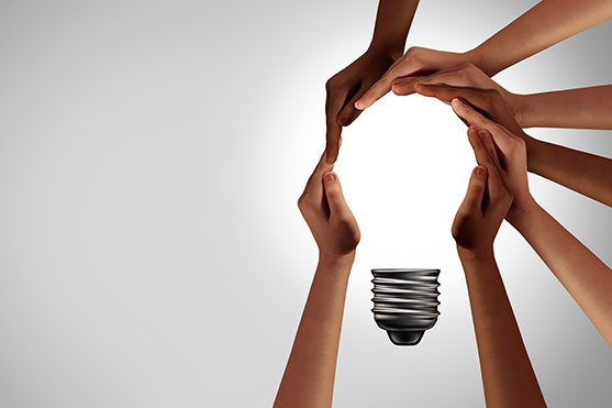 hands of different races form the shape of a light bulb