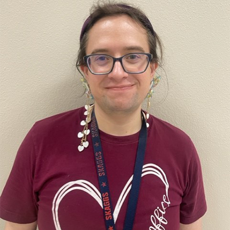 The Skaggs CTA, Éowyn MacBeth (pronounced A-oh-win), smiling in her maroon Skaggs Office Team shirt.