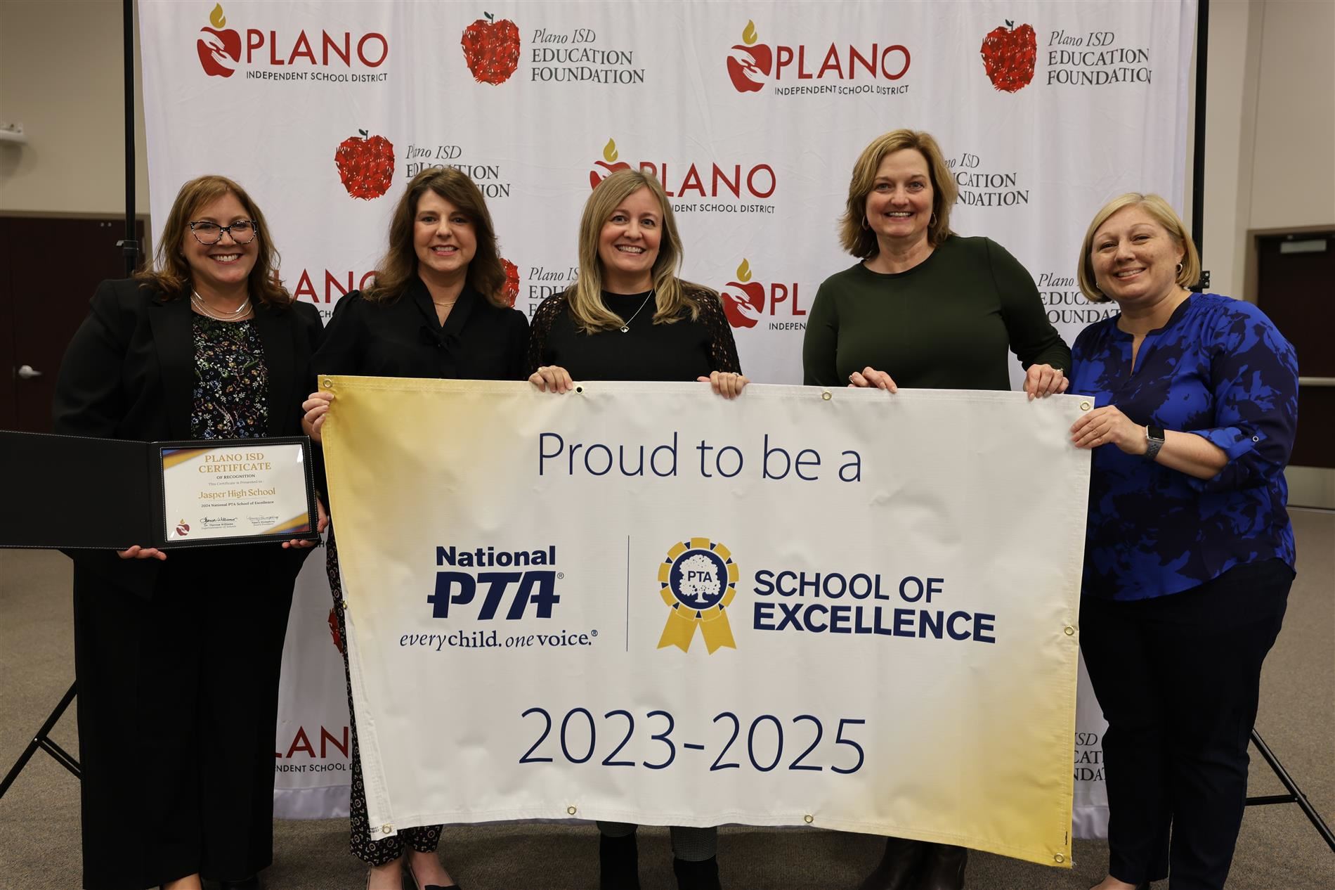 Multiple individuals standing behind a PTA School of Excellence banner