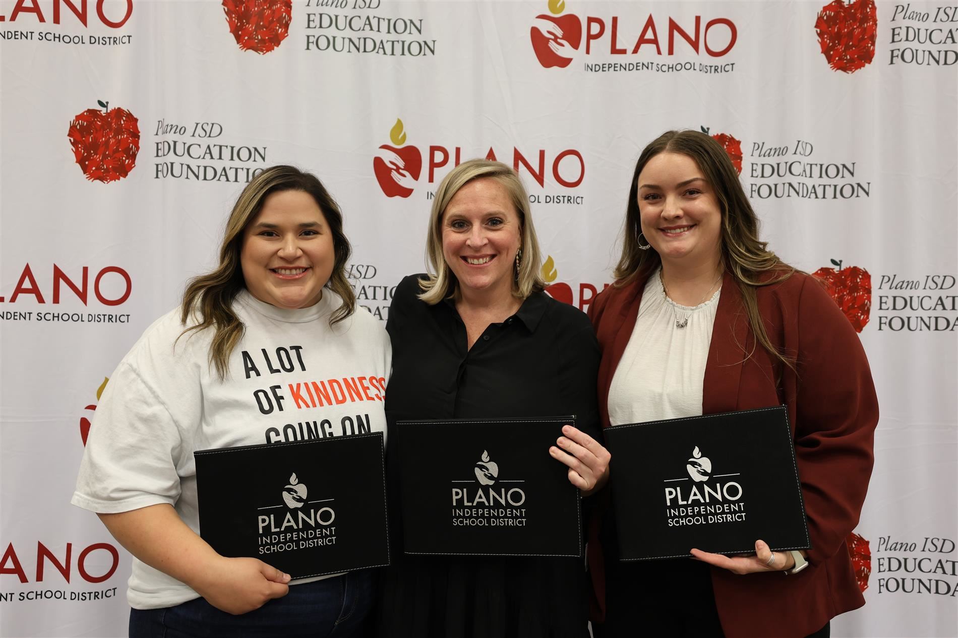 three individuals standing with awards in front of the Plano ISD logo and Education Foundation logo
