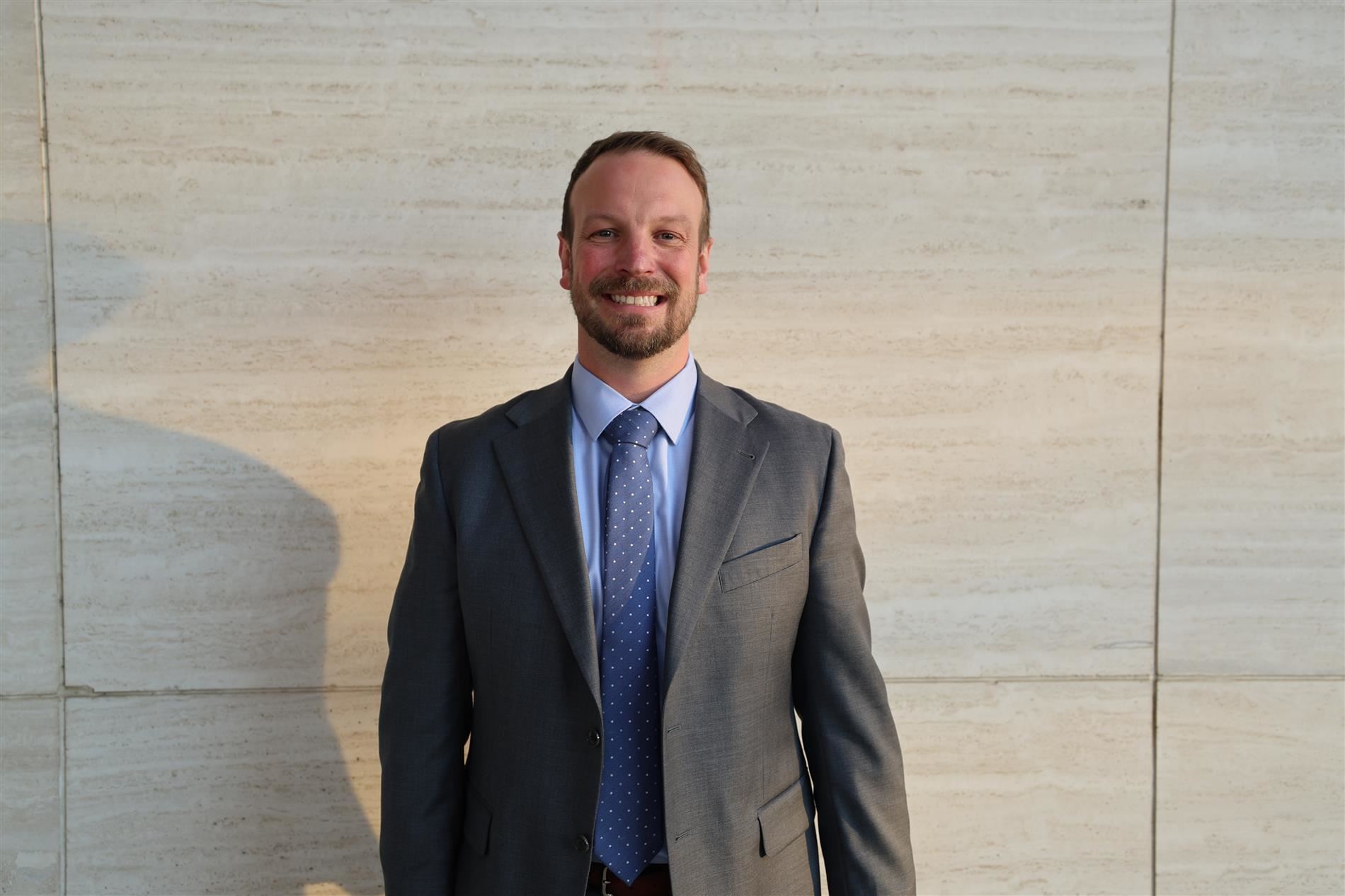 Brad Bailey smiling in front of a stone backdrop