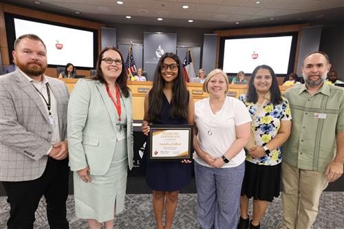 individuals posing in front of the Plano ISD Board of Trustees Dais 