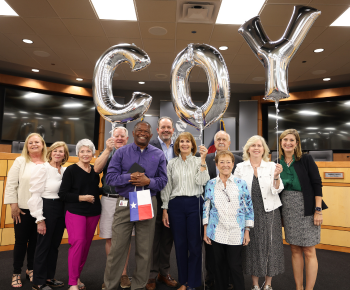  A group of individuals holding balloons that say "COY"