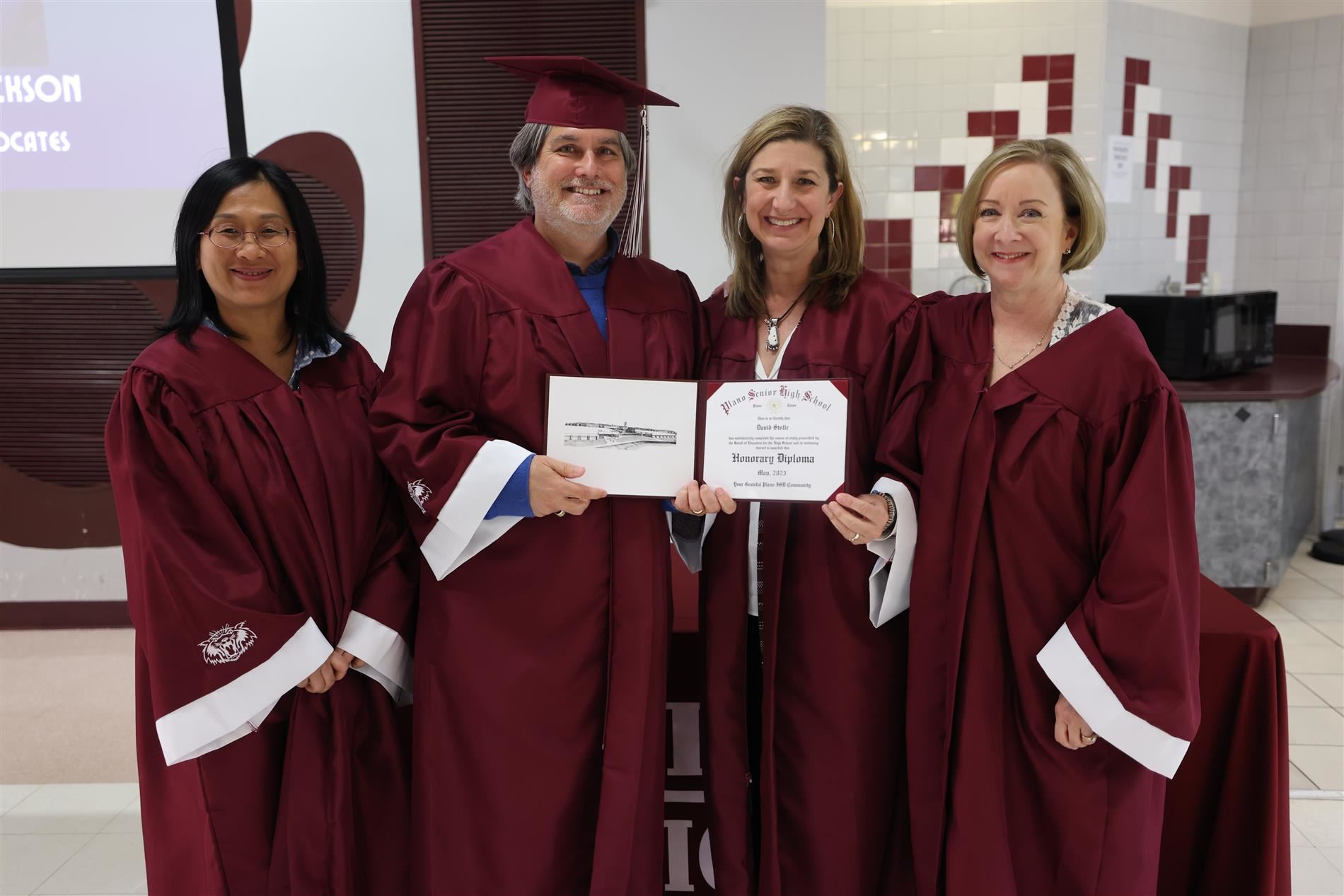 Board President Stolle with cap and gown, earned an honorary diploma from Trustees Dr. Heather Wang, Jeri Chambers and Board 