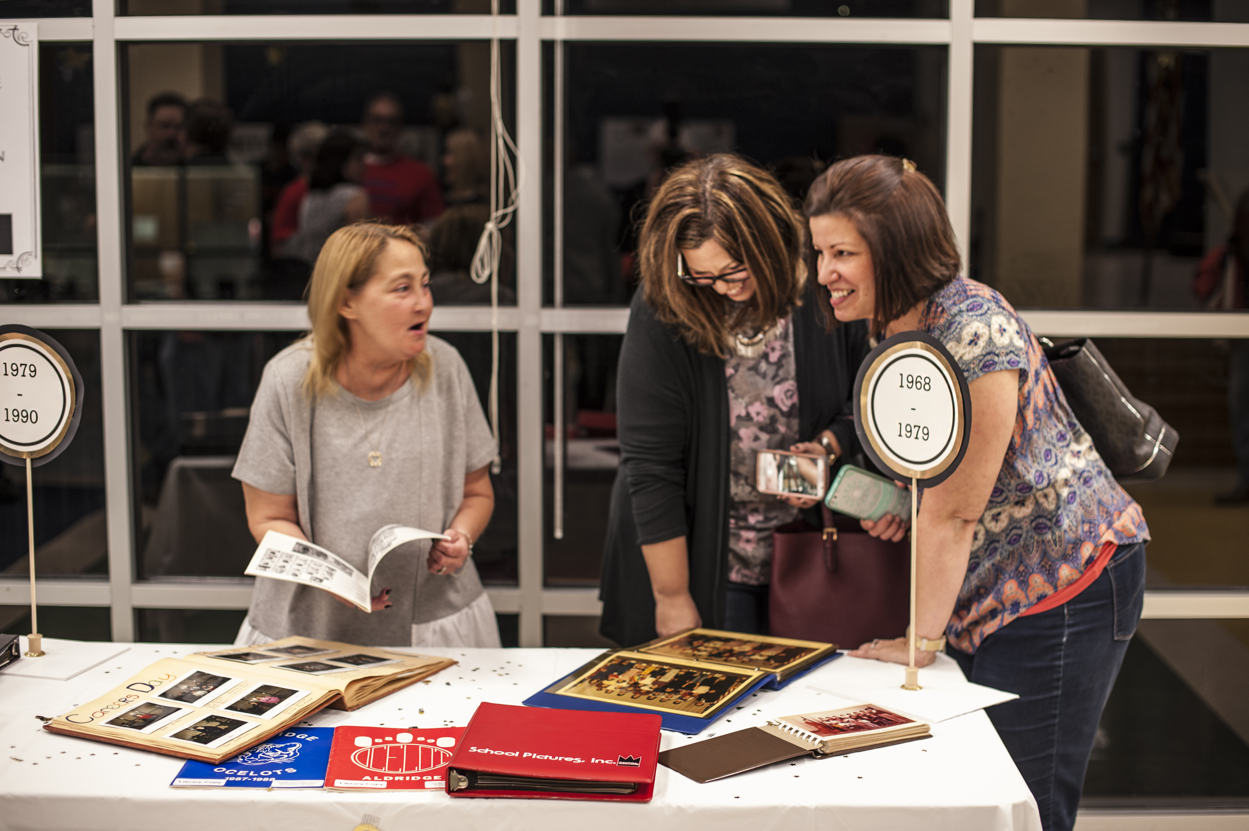 three women looking at old yearbooks 