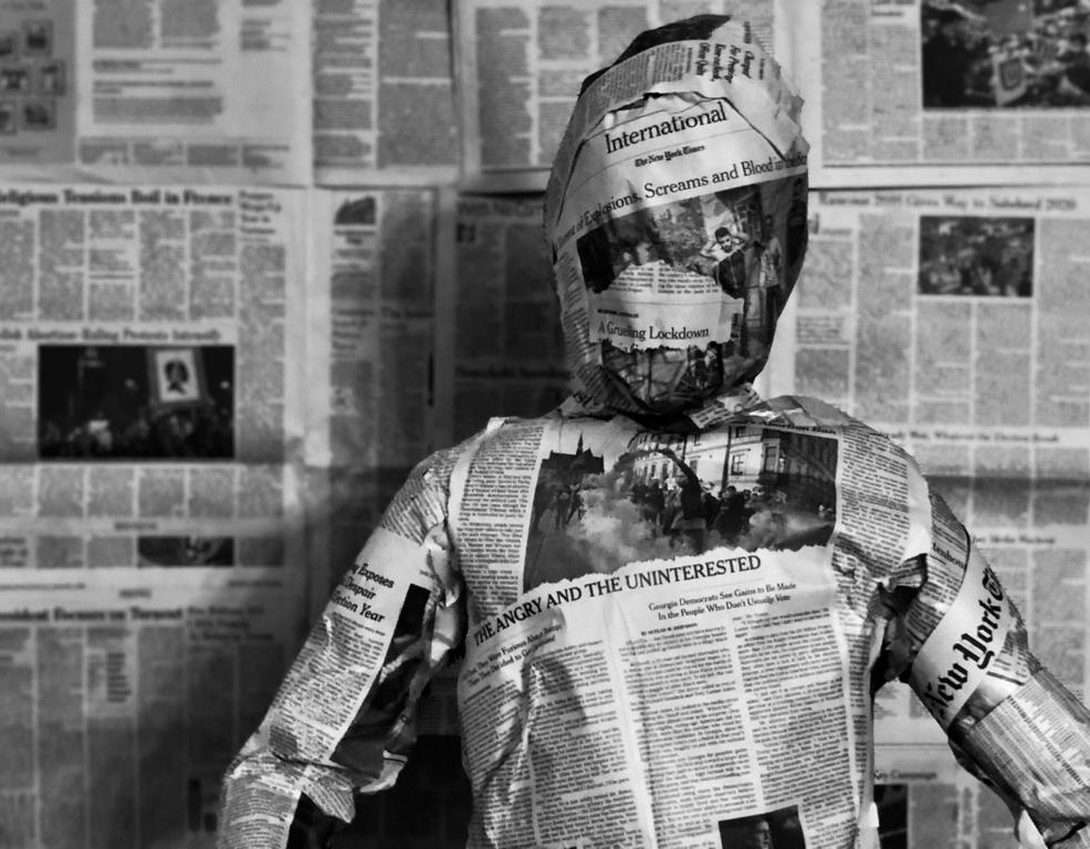 Awake from Ignorant Slumber - person wrapped in newpaper with headlines 