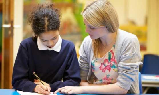 Teacher working with student writing on paper 