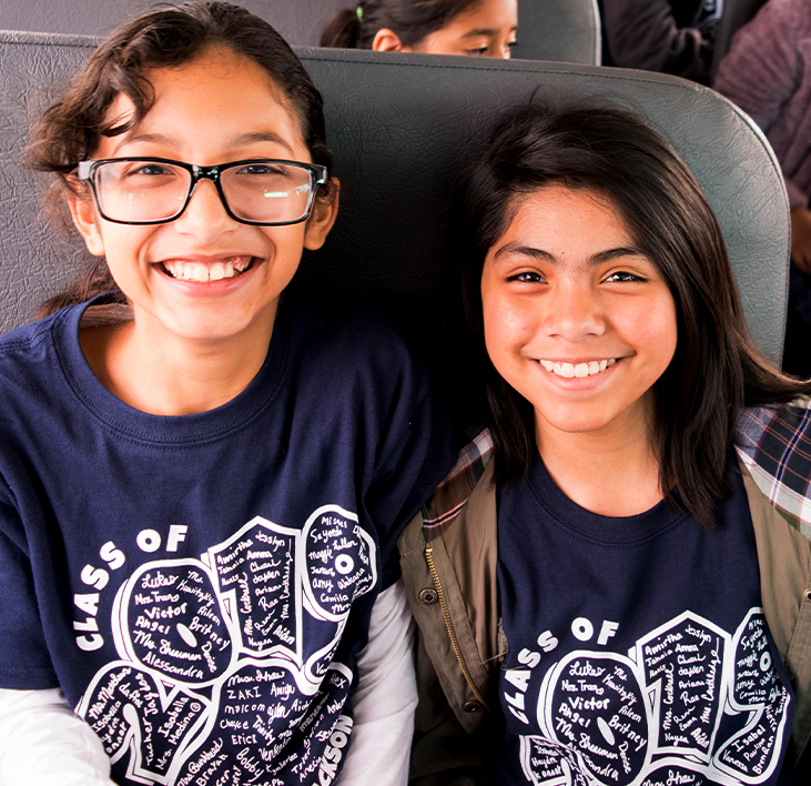  2 girls in camp shirts on the bus to camp