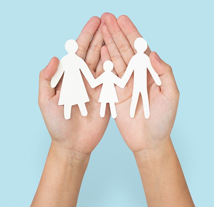  two hands palms up holding paper cutout of a family
